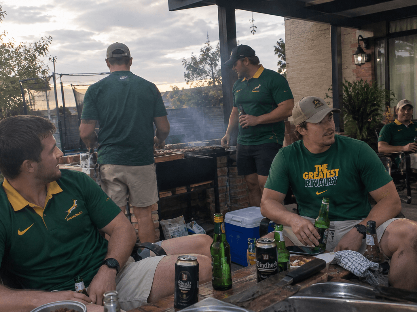 Group of men in Springbok shirts around a braai at sunset